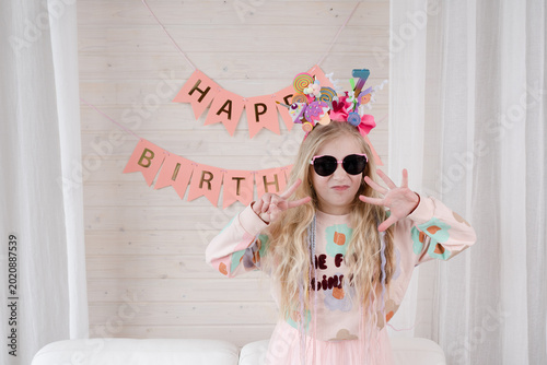 Amazing small blond girl celebrating birthday. Decoration and photo zone for girls birthday party