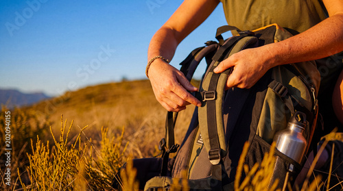 Φωτογραφία Close up of a person's hands adjusting the straps of a hiking backpack in a natural, sunny outdoor environment