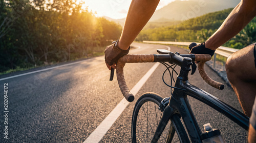 фотографія Close-up of a cyclist's gloved hands on bicycle handlebars, riding a road bike on an open road at golden hour