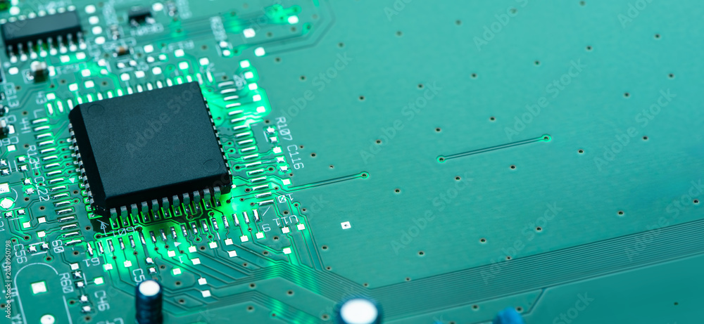 Foto Close up of electronic circuit board with microchip processor, glowing green PCB