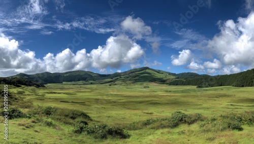 Vast Green Rolling Hills Under a Dramatic Blue Sky with Fluffy Clouds.