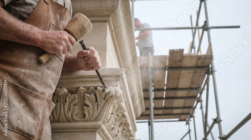 Stonemasons in dusty aprons use hand chisels on ornate limestone cornice of nineteenth-century municipal building, scaffolding framing carve 3