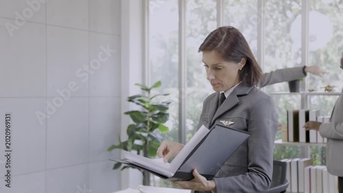 The airline manager is reviewing the work documents of his team members.