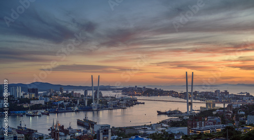 Bild auf Leinwand Stunning sunset over a vibrant urban waterfront and bridge.