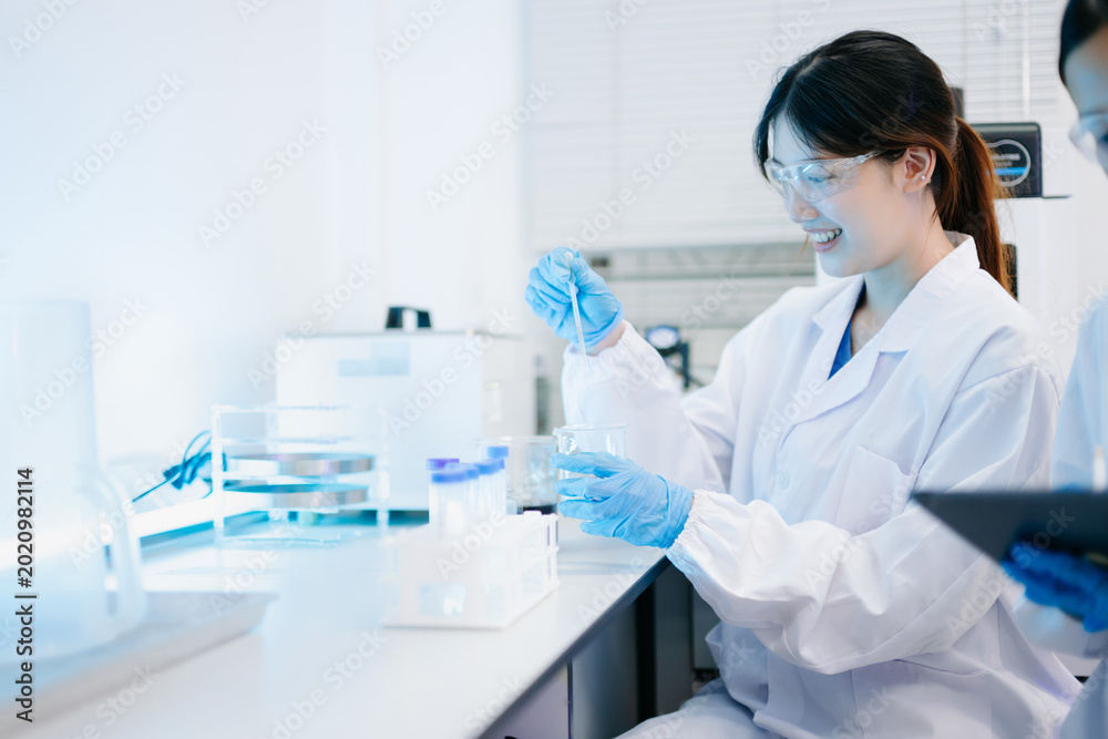 Fototapeta premium Two scientist or medical technician working, having a medical discuss meeting with an Asian senior female scientist supervisor in the laboratory with online reading, test samples