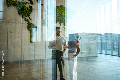 Quadro su tela Business partners discussing global strategy in eco-friendly office lobby