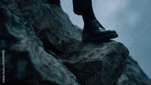 Close-up of a persons shoe standing on a rocky cliff edge.