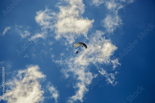 Photos Skydiver descending with open parachute against blue sky