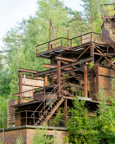 Billede på lærred Abandoned industrial factory infrastructure decaying in overgrown nature