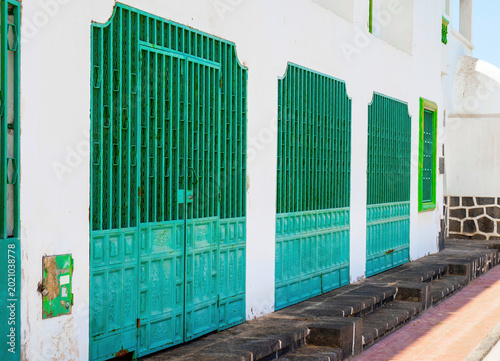 Traditional turquoise doors on white urban house facade in sunny street