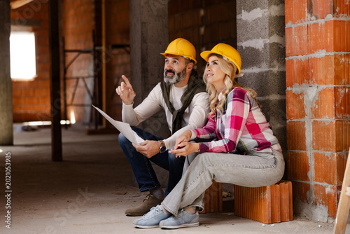 Couple Review Building Plans Inside a Work Site