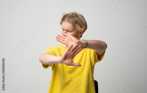 Fotografie Young man using hands gesture signaling stop and refusal, creating a boundary, r