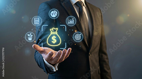Professional businessman holding a glowing virtual money bag icon representing financial growth and investment success strategy