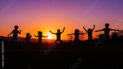 Silhouetted children joyfully leaping against a vibrant sunset sky