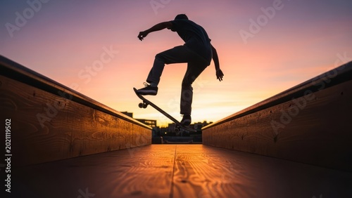 Skateboarder silhouetted in mid-air against a sunset