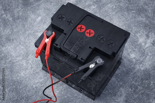 Old car lead acid battery with charging clamps during repair process, maintenance, and attempt of capacity restoration.