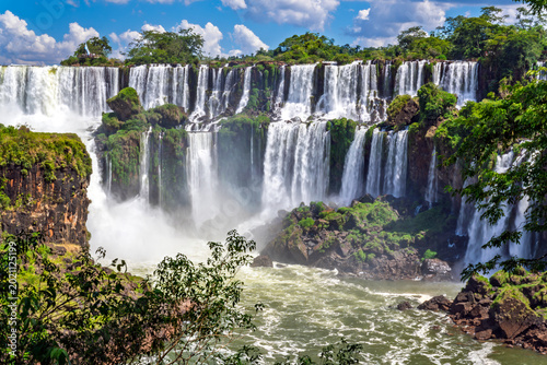 Majestic Iguazu Falls panoramic view with lush green tropical rainforest and blue sky, Misiones, Argentina