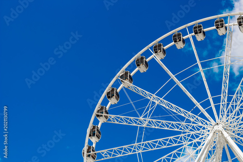 Foto Ferris wheel stands tall in blue sky at amusement park during bright daytime wit