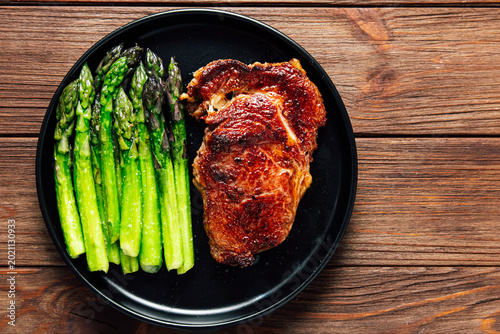 Obraz na plátne Grilled steak served with fresh asparagus on a black plate during a midday meal