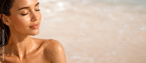 Portrait of young woman with wet skin and water droplets on shoulder enjoying sun on tropical beach with copy space