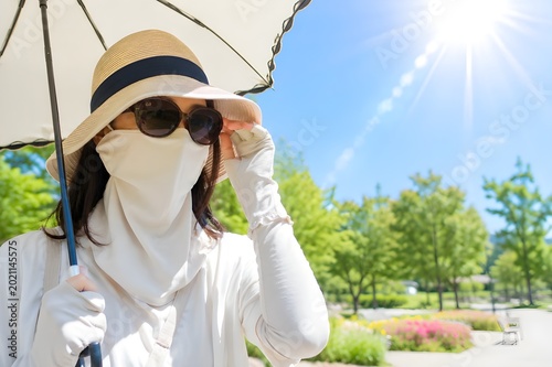 夏の強い日差しの中で徹底した紫外線対策をする女性の日焼け防止と熱中症対策イメージ（AI生成）