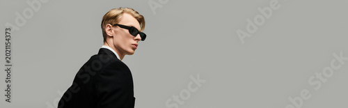 Foto Stylish young man in sunglasses showcases modern fashion sense against a neutral