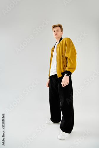 Stylish young man poses confidently in trendy outfit with modern flair