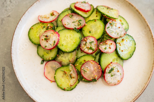 Photos spring salad with cucumber radishes and honey mustard dressing in a bowl close u