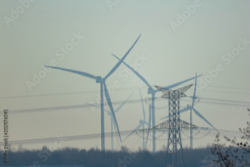 High voltage power lines and wind turbines in a hazy landscape, energy transition concept