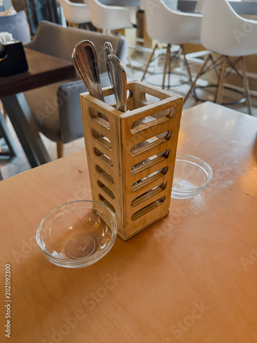 A Stylish Wooden Cutlery Holder with Spoons and Glass Bowls on a Restaurant Table