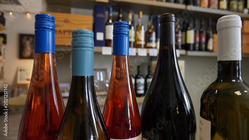 Selective focus on wine bottles in a boutique wine store with blurred shelves in the background.