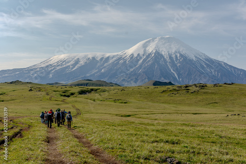 Tableau sur toile group of people walking along a dirt road towards a volcano