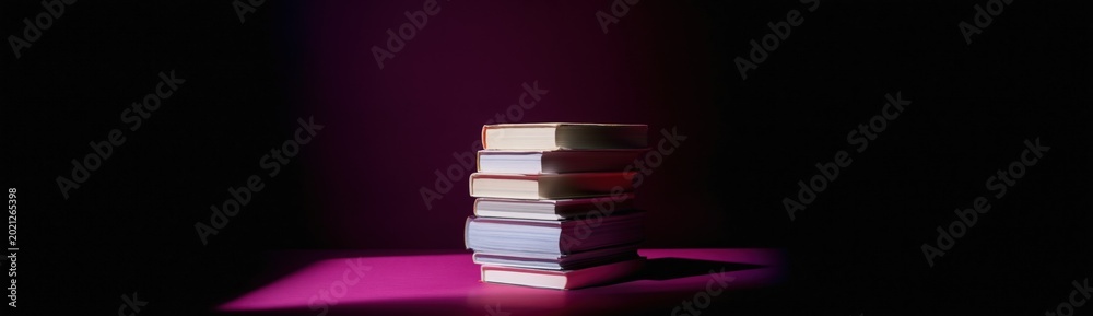 Fototapeta premium Books stacked under spotlight on dark stage surface