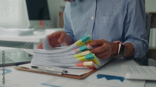 Close up of a female office worker hands searching for a specific document in a large pile of paperwork stacked on her office desk