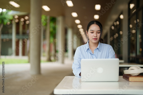 Cuadro en lienzo Focused Asian female student studying with a laptop outdoors on a university cam