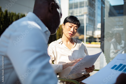 Business professionals reviewing financial reports outdoors at modern office
