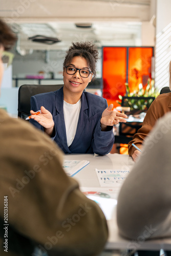Young businesswoman leading team discussion in modern office meeting
