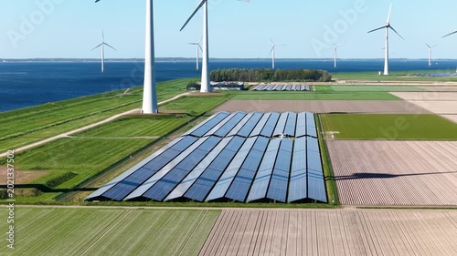 Aerial drone view of solar panels and wind turbines in a renewable energy farm. Sustainable green power station for clean electricity production and environmental technology infrastructure.