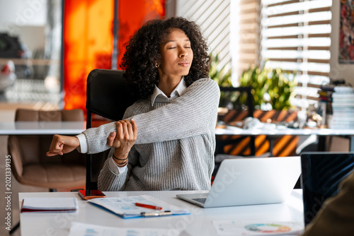 Fotografía Young woman stretching arm enjoying a wellness break in office