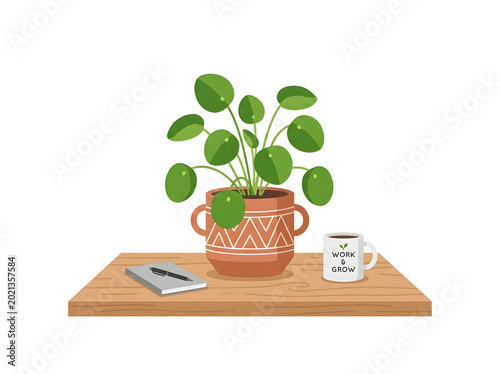 Potted plant on a wooden table with a mug and book