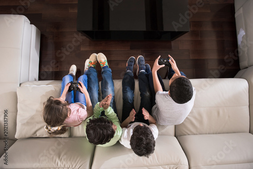 Cuadro en lienzo Modern Middle Eastern family kids playing video games together on couch during E