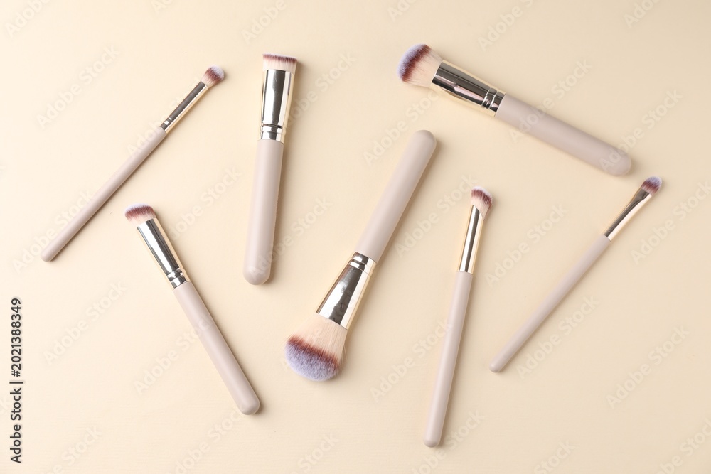 Fototapeta premium Many clean makeup brushes on beige background, flat lay