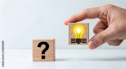 Hand holding a lightbulb cube next to a question mark cube, symbolizing idea generation