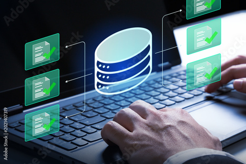 Data-driven Operation: A person meticulously navigates a laptop, with digital representations of data storage and document verification, illustrating data processing and operational efficiency.