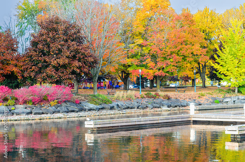 Fall colors in a park reflected in water with docks in the foreground
