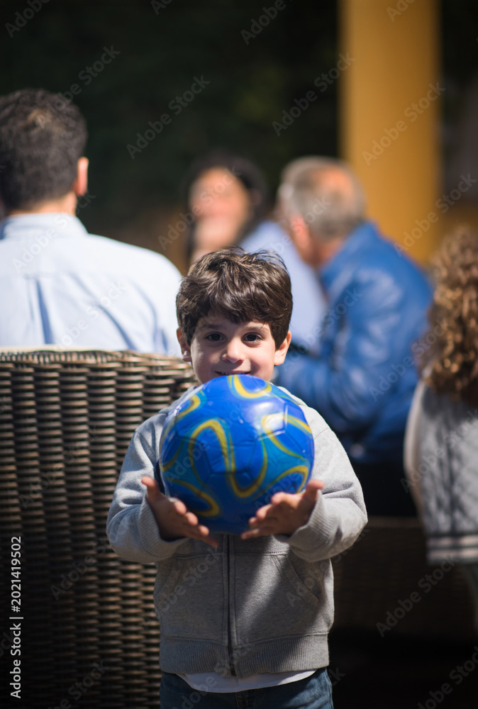 Fototapeta premium Middle Eastern family celebrating Eid Ramadan iftar with young boy holding a soccer ball at modern home