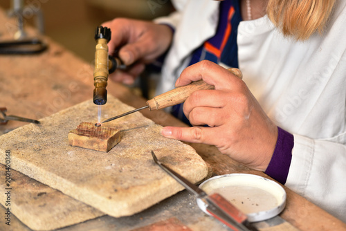 A female jeweller making a soldering of the silver jump ring