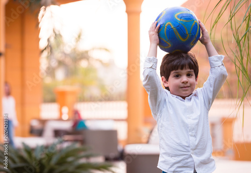 Foto Young boy holding a colorful ball during Eid family gathering at a modern home