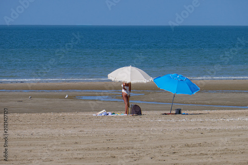 scène de plage avec 2 parasols et une femme