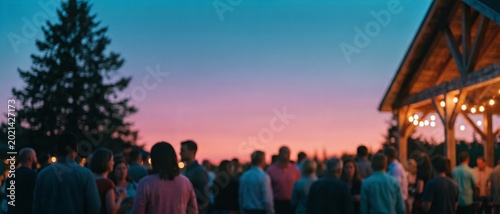 Defocused silhouette of large crowd of people gathering at sunset